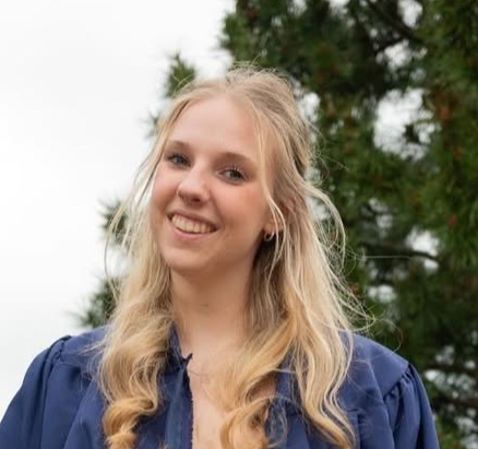 picture of a person with long blonde hair with a tree in the background