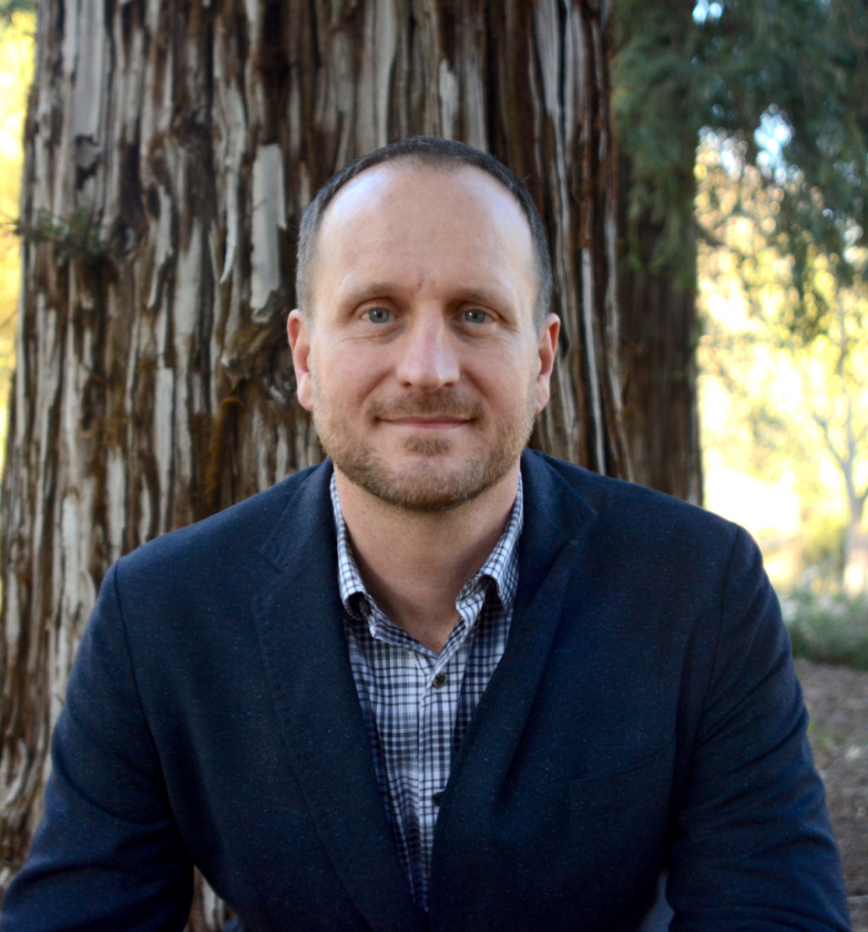 image of a person with short hair and a tree in the background